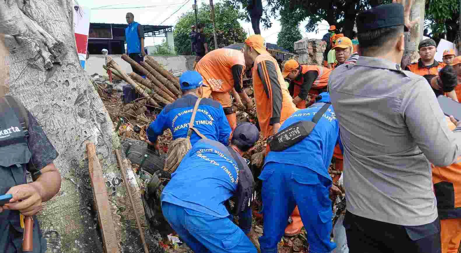 Petugas gabungan tengH merapihkan tnaggul yang kali yang jebol