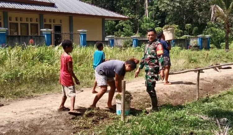 Peduli Lingkungan, Babinsa Supiori Bersama Warga Gotong-Royong Bersihkan Rumput Liar di Bahu Jalan